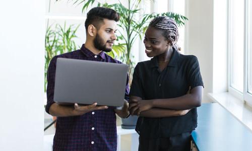 Two students discussing work on a laptop